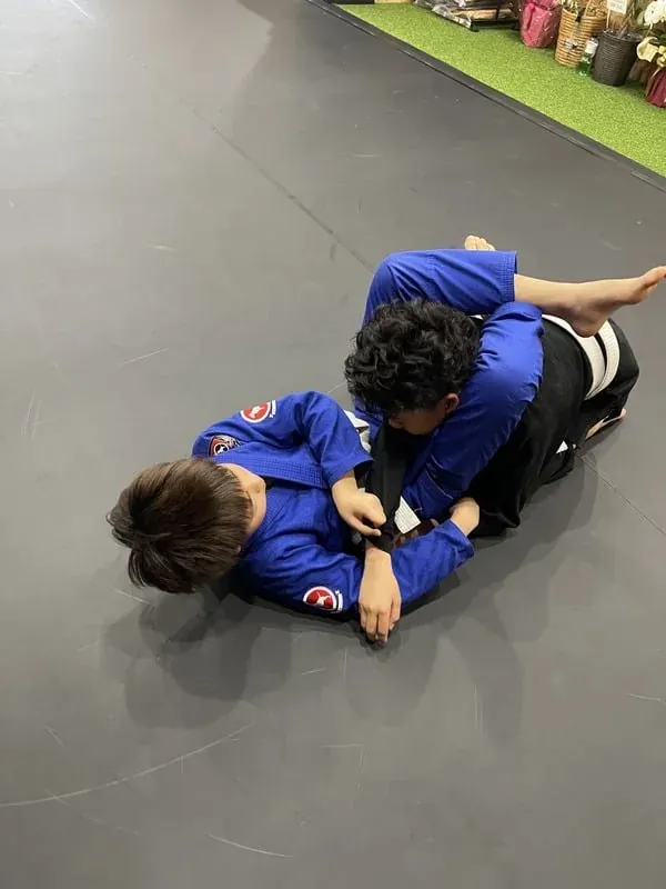 マットの上で寝技を練習する子どもたち